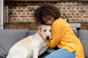 mujer abrazando a su perro en el sofá