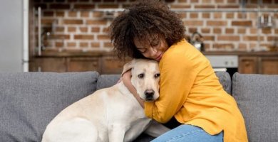 mujer abrazando a su perro en el sofá