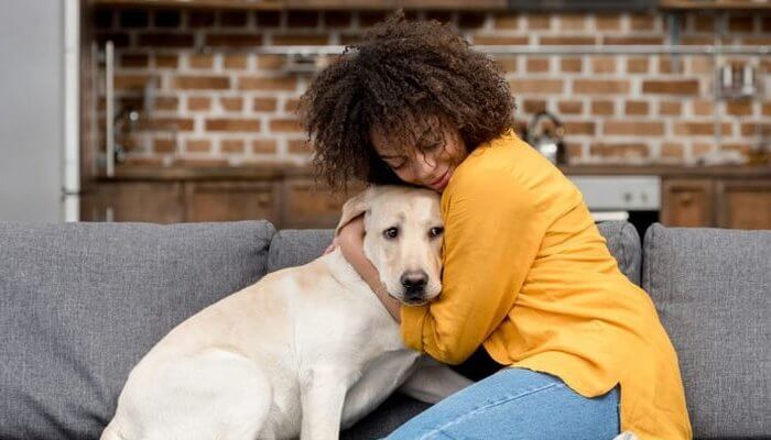 mujer abrazando a su perro en el sofá