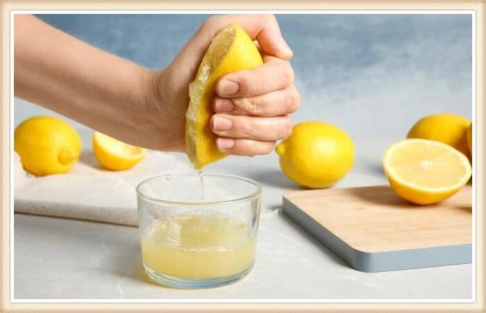 mano exprimiendo jugo de limón natural en frasco de cristal