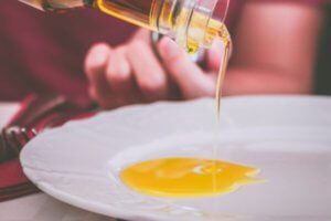 persona sirviendo aceite de oliva en plato