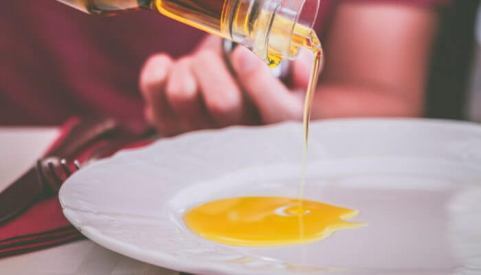 persona sirviendo aceite de oliva en plato