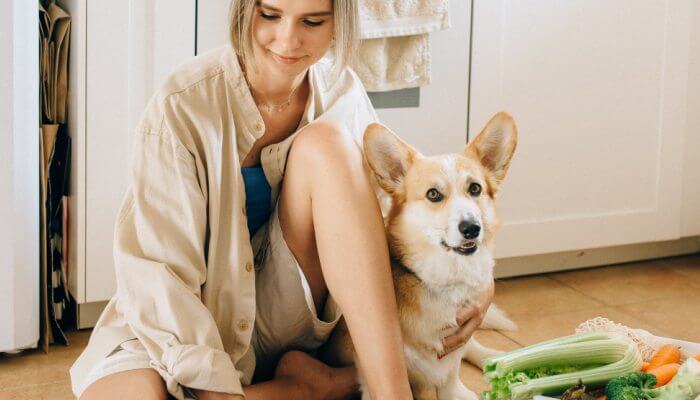 perro y duena sentados junto a verduras